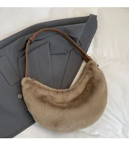 Detailed view of plush dumpling bag with leather strap on a grey suit background