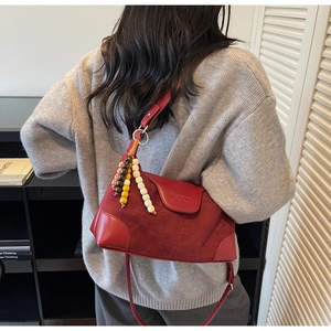 Detail view of burgundy leather dumpling bag with decorative wooden beads and shoulder strap