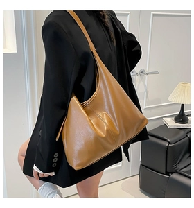Close-up of a vintage brown glossy leather tote bag showing soft texture and wide strap