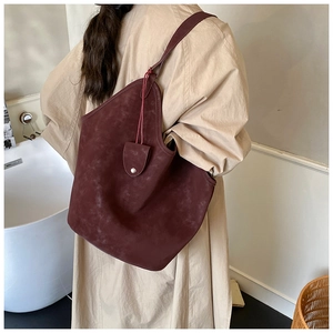 Detail of burgundy suede tote bag showing soft matte texture and silver metal button buckle