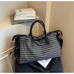 Detail of travel duffel bag with grey textured fabric, leather trim and adjustable strap