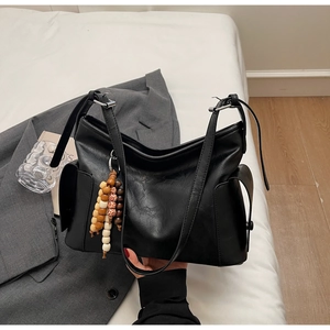 Close-up of black PU leather hobo bag featuring colorful wooden beads and side pockets