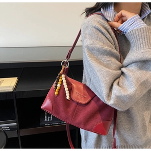 Detail of burgundy suede shoulder bag with colorful wooden bead tassel decoration