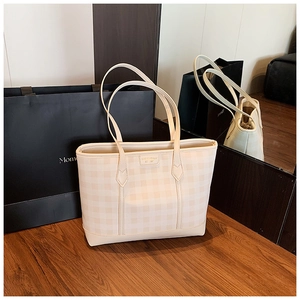 Close-up of the beige plaid pattern and leather logo plaque on this commute tote bag