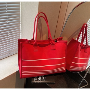 Detail of red canvas tote bag featuring white parallel stripes and spacious interior design