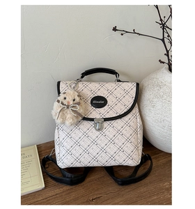 Detail of plaid backpack with metal buckle, top handle and plush rabbit pendant