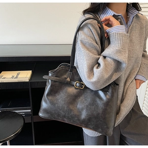 Détail d'un sac cabas noir vintage avec boucle en métal doré et texture en similicuir