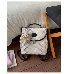 Detail of cream plaid mini backpack with silver buckle and plush bear pendant accessory