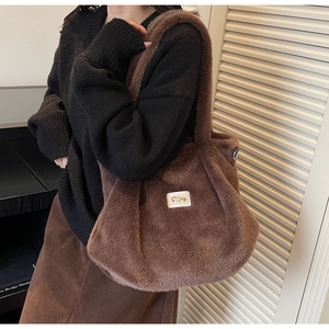 Détail du tote bag en peluche marron montrant la texture douce et l'étiquette perle