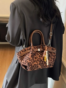 Retro leopard print bucket bag with leather handles and beaded tassel charm on a model