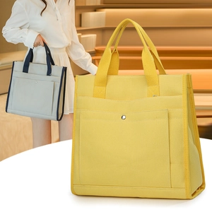 Close-up of large canvas tote bag with metal buckle pocket and wide shoulder straps