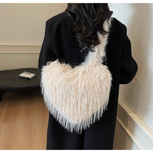 Détail du sac à épaule en peluche en forme de cœur en fausse fourrure crème sur modèle