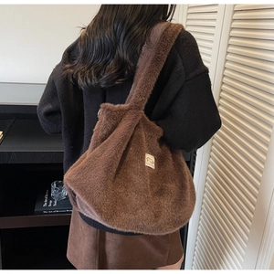 Gros plan sur la texture en fausse fourrure marron et l'écusson du sac cabas peluche