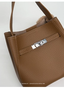 Detail of brown lychee grain leather with silver twist lock on retro bucket bag