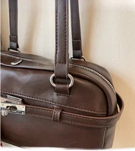 Detailed shot of brown leather Boston bag with silver rotating metal lock and zipper