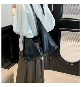 Detail of minimalist black hobo tote bag in oily finish faux leather with wide strap