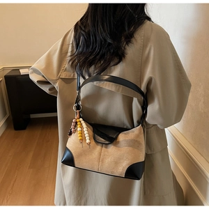 Detail of a chic patchwork suede dumpling bag showing its large capacity and beaded charm