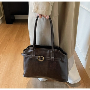 Détail du sac cabas en cuir marron foncé avec boucles dorées et fines bandoulières
