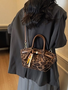 Leopard print bucket bag with leather handles and colorful beaded charm on a model