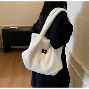 Détail du grand sac cabas en peluche blanche montrant sa texture douce et son écusson en cuir