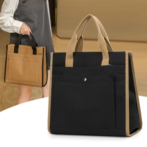 Close-up of contrast color canvas tote with thick webbing handles and outer pocket detail