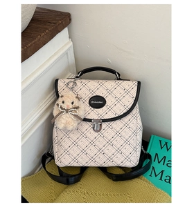 Detail of beige plaid backpack with black polka dots, leather handles and plush pendant