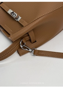 Detail of silver twist lock and lychee texture on brown leather bucket handbag