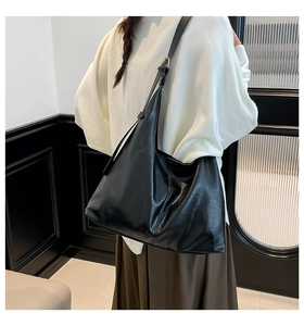 Side view of a large black vintage leather tote bag worn by a model in a minimalist room