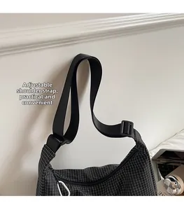 Détail de la bandoulière large réglable noire sur un sac besace en toile à carreaux