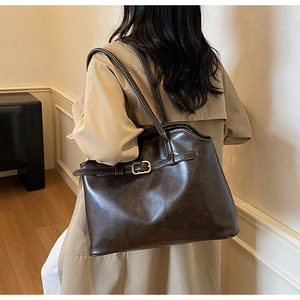 Détail du sac cabas marron foncé avec boucle métallique décorative et bordure ondulée
