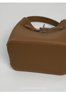 Detail of brown lychee grain leather bucket bag with silver metal twist lock and stitching