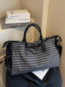 Gray herringbone travel duffel bag with black leather trim and adjustable shoulder strap