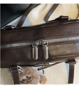 Detailed macro view of smooth silver double zippers and litchi texture on coffee leather bag