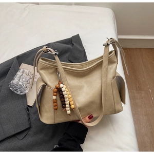 Close-up of beige leather crossbody bag with side pocket and colorful wooden bead charm