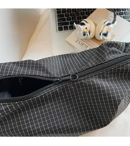 Détail de la fermeture éclair en métal sur le sac à bandoulière en toile à carreaux
