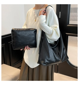 Detailed look at the black textured hobo bag and matching pouch on a model in a minimalist room