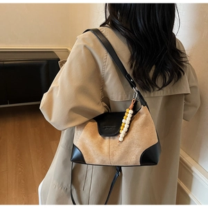 Detailed back view of a brown suede hobo bag with black leather trim and bead pendant