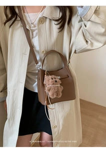 Brown lychee leather bucket bag with cute plush bear charm and adjustable strap