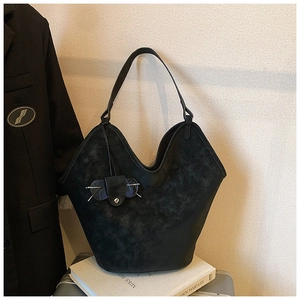 Detail of black suede tote bag with unique V-shape opening and small sunglasses pouch charm