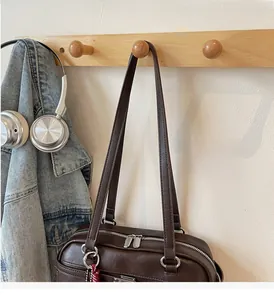Detail of dark brown shoulder bag with double zippers and stylish fabric charm detail