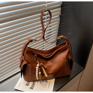 Detail of a brown vintage crossbody bag with a colorful beaded tassel and soft PU leather