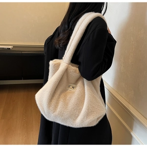 Détail du sac cabas beige en peluche avec logo en métal perlé et texture en fausse fourrure