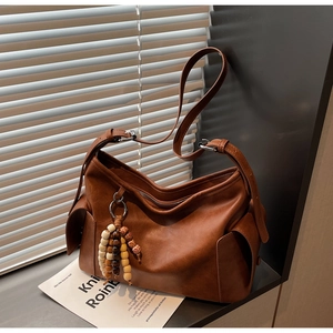 Detailed close-up of retro caramel leather hobo bag with unique wooden bead tassel detail