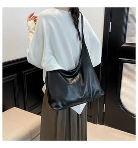 Detail view of a large black faux leather hobo shoulder bag with textured finish