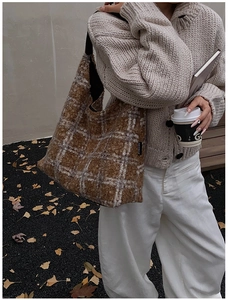 Détail d'un sac cabas en laine à carreaux marron avec texture douce et bandoulière noire