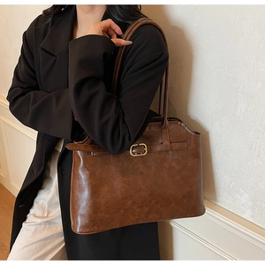 Détail du grand sac cabas marron en cuir synthétique avec boucle métallique sur la bandoulière