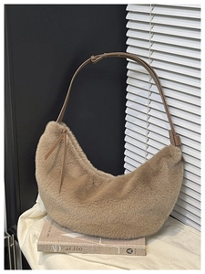 Detailed macro of plush faux fur crescent bag with adjustable brown leather shoulder strap