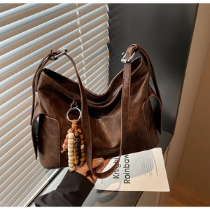 Detail of vintage brown tote featuring textured faux leather and wooden bead charm