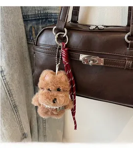 Detailed view of brown plush dog pendant with pearl necklace on leather handbag