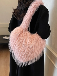 Sac à épaule en peluche rose en forme de cœur porté par un mannequin dans un décor épuré